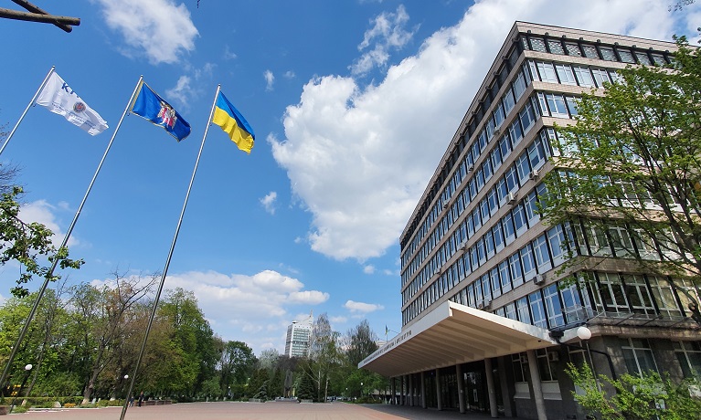An exterior shot of a building at Kyiv National University of Construction and Architecture with three flags flying in the foreground including the Ukraine flag