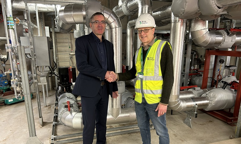 Dr Clive Winters from Coventry University and Ian Parker from Bring Energy shaking hands in a plant room with pipework in the background