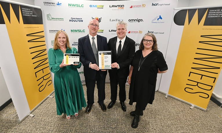 Two women and two men in smart clothes smiling at the camera at an awards ceremony