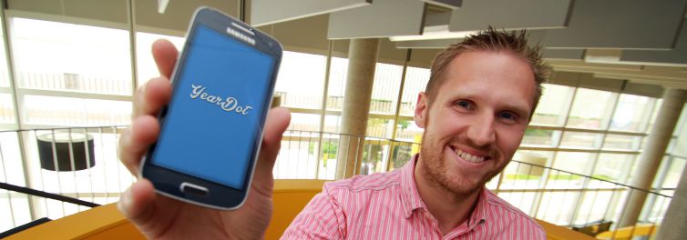 A man holding up a phone showing the new app logo