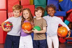 Four children about seven years old, each with one arm around another's shoulders and each holding a ball