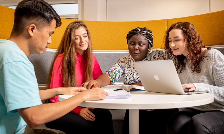 Four students sitting at a table working together