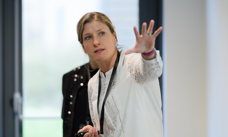 Coventry University researcher Louise Moody in a white top gesturing with her hand and looking off to the right of the camera