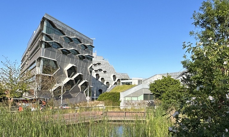 Coventry University's EEC building on a sunny day with trees and grass in the foreground