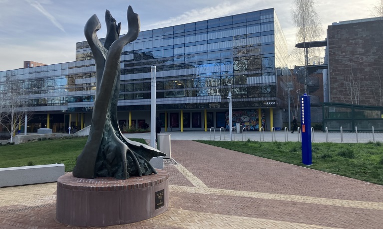 The Phoenix Tree sculpture in Coventry University's new peace garden with TheHub in the background