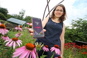 A woman using a new app among some flowers in a garden