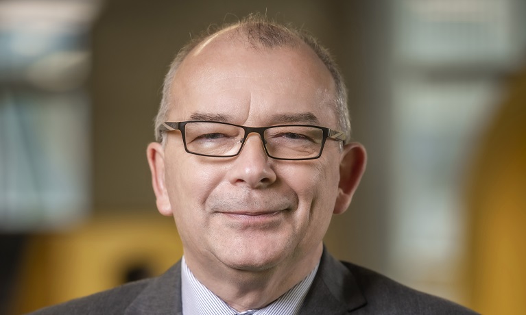 A head and shoulders picture of a man against a blurred background