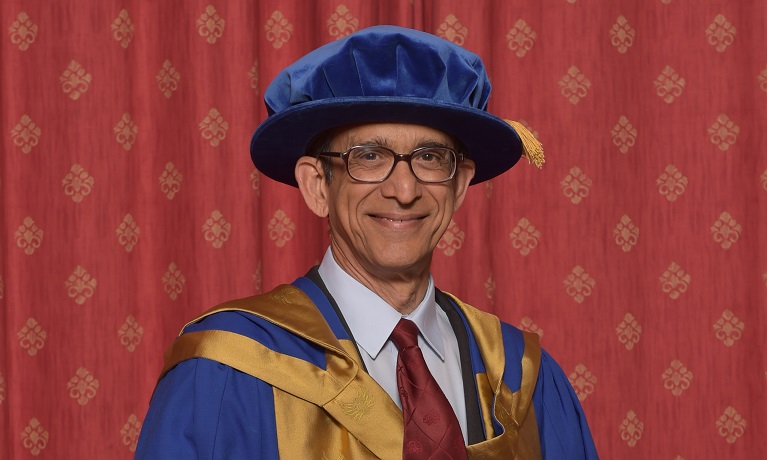 Ravi Pandit smiling at the camera wearing his honorary gown and hat