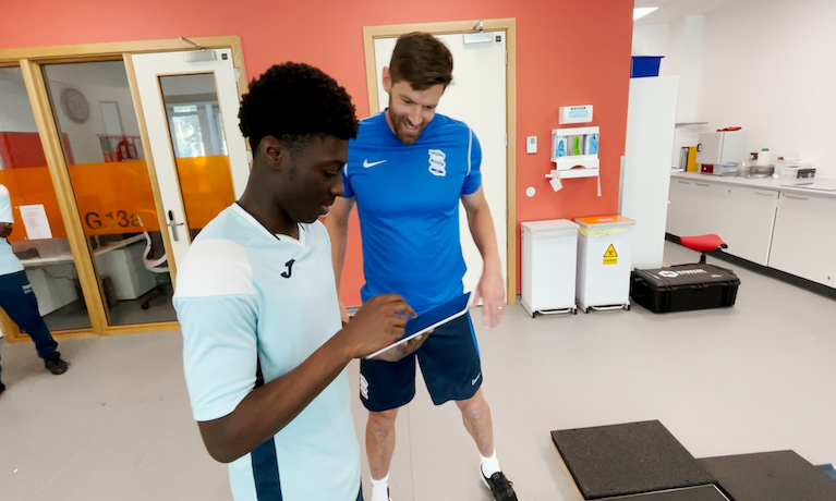Coventry University student Joshua Asamoah shows Lukas Jutkiewicz the results of a physical assessment on an iPad