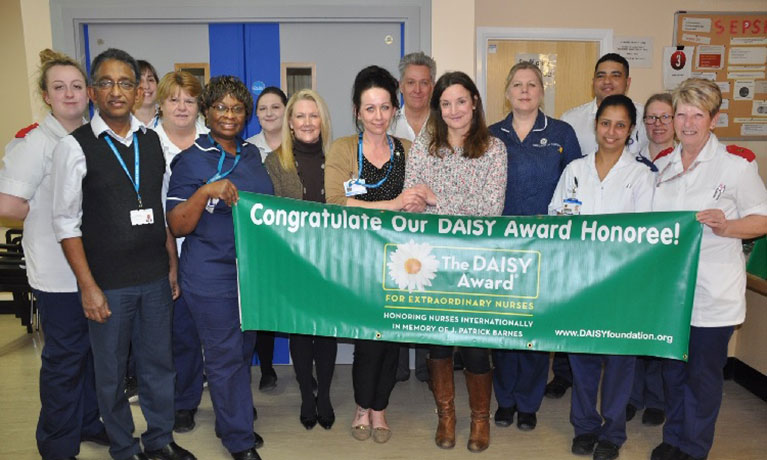 Nurses and staff standing behind a DAISY Foundation banner