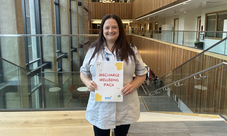 Leanne Howlett holding the wellbeing pack she created for patients