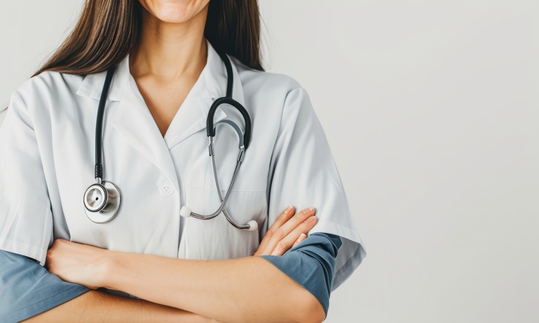 The body of a female health worker in a white coat and a stethoscope around her neck