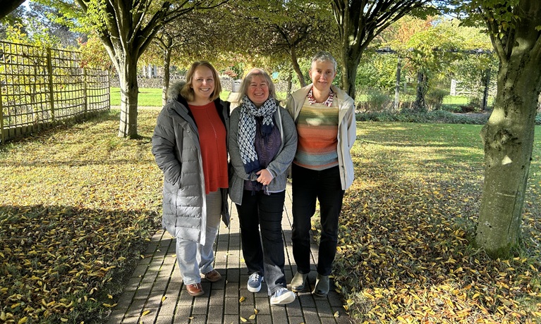 Dr Jana Fried, Dr Liz Trenchard and Dr Katharina Dehnen-Schmutz stood under some trees in a green garden
