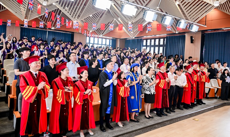 Staff and students in graduation gowns clapping at the ceremony at Communication University of China