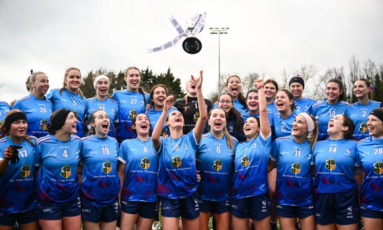 Coventry University women's Gaelic Football team crowd around their captain as she throws the trophy into the air