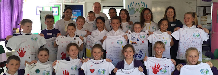 Students holding their painted t-shirts and handprints made for Iraqi children