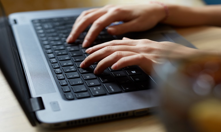 a person's hands typing on a keyboard