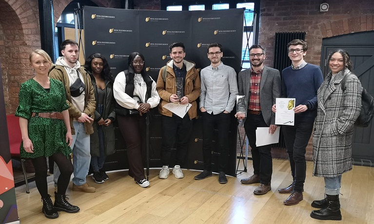 A group of students standing in front of an awards banner