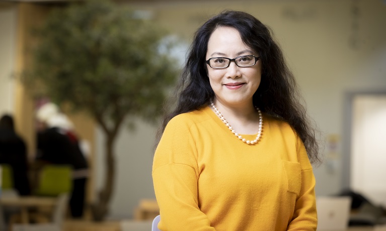 A woman wearing a yellow jumper against a blurred background