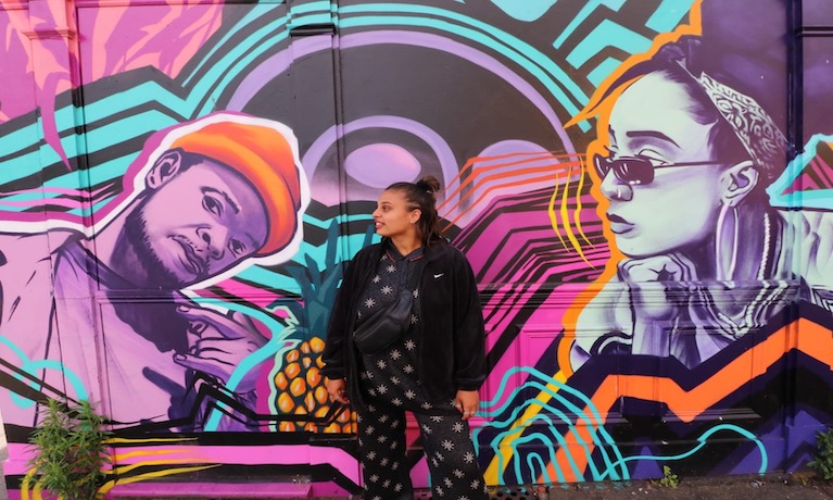 Shaniece Martin posing in front of a colourful mural
