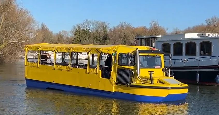 A yellow amphibious bus travelling along a river
