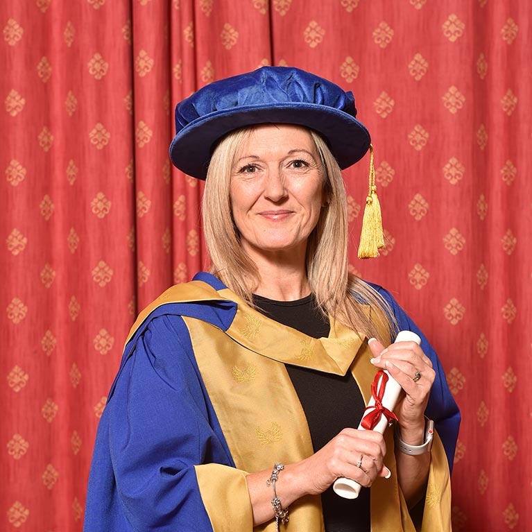 Adult woman wearing official clothing and folding a diploma document