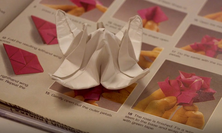 A still image from the film showing a paper flower on a book