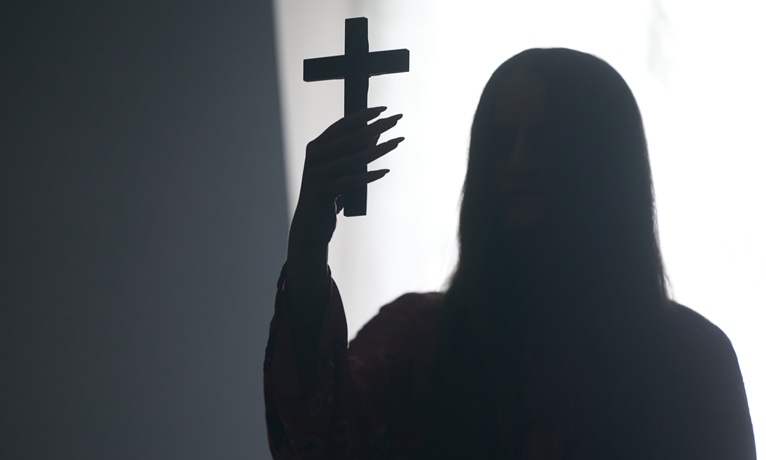 A silouhette of a woman with long hair holding a cross