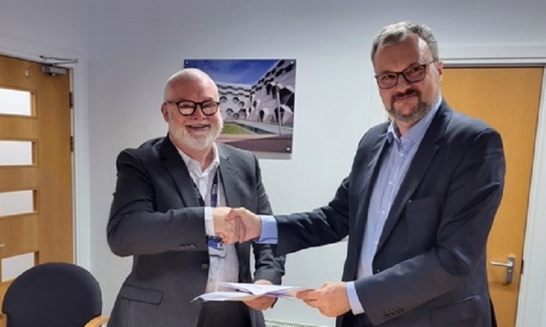 Two men shaking hands holding a document
