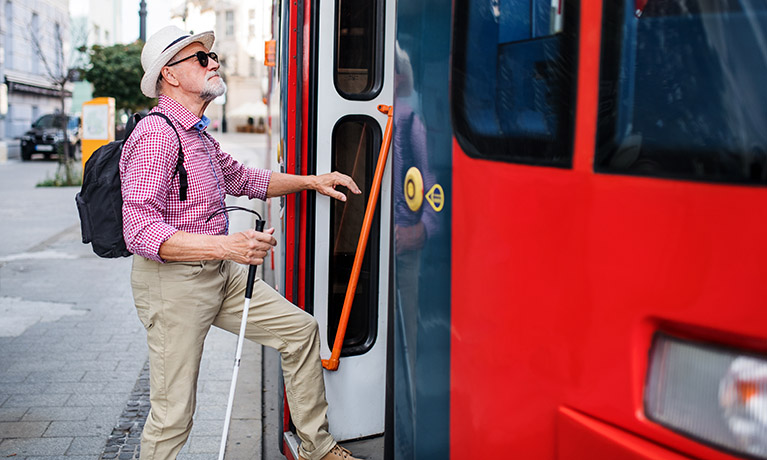 A picture of a man wearing dark glasses stepping onto a bus