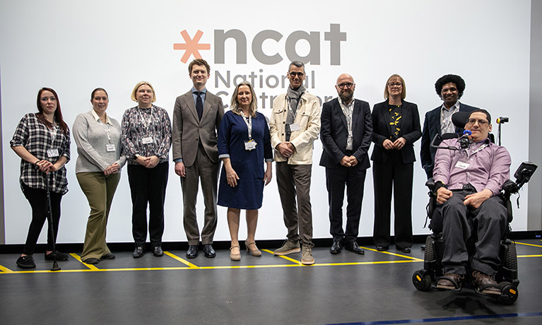Representatives of the NCAT consortium group in front of the NCAT logo