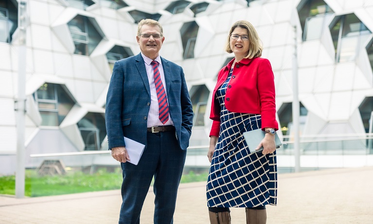 A man and a woman standing in front of Coventry University's EEC building