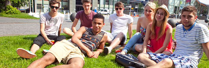 Students sitting on grass in the sunshine