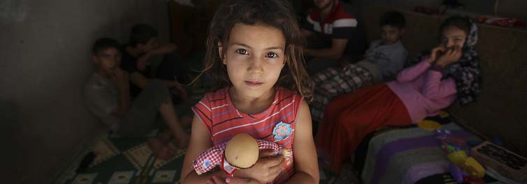 Refugee children the child in the foreground cuddling a toy