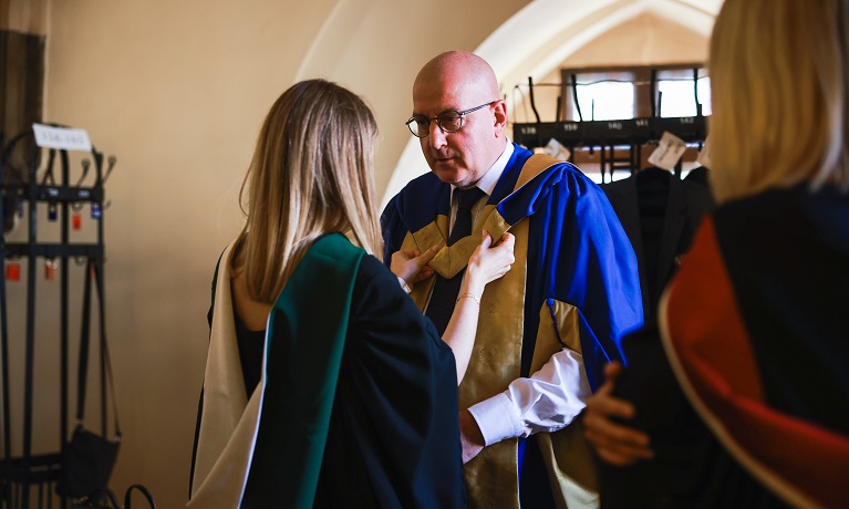 Dr Rafał Dutkiewicz is helped with his graduation gown at the Coventry University Wrocław graduation ceremony