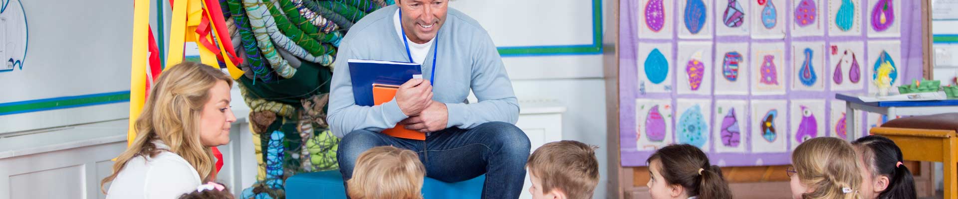 a group of children sat around a teacher, ready to read a book