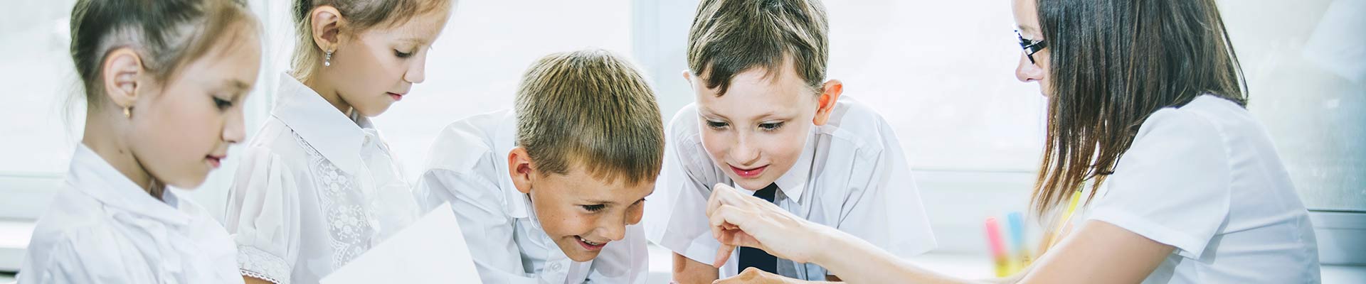 Students in school doing an activity with a teacher helping