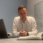 Andy McCall next to his laptop infront of a whiteboard