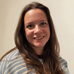 Naomi smiling at the camera with a plain background