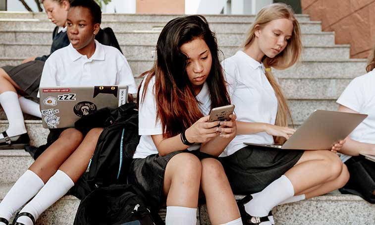 Group of students sitting on steps, using devices