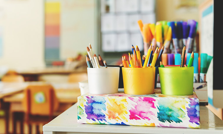 Pots of coloured pencils and pens in a primary school classroom