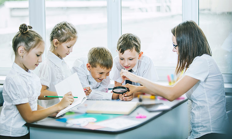 Students in school doing an activity with a teacher helping