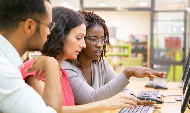 Two teachers being mentored while using a computer