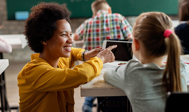 A teacher helping a student at their desk