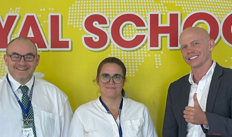 Joshua James in a suit with two other people, smiling at the camera and giving a thumbs up.