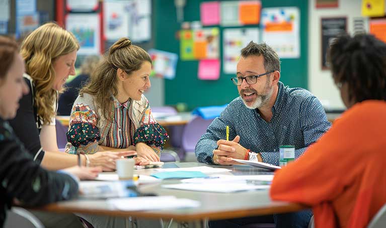 Group of teachers sitting around a table in a classroom 