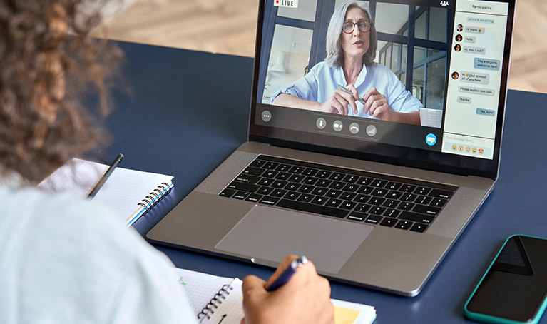 A person with curly hair watching online training on a laptop.