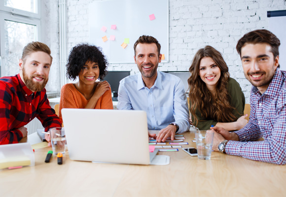 A group of people at a table with an open laptop in front of them.