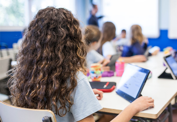 Secondary school students studying in class with tablets propped up on the tables in front of them