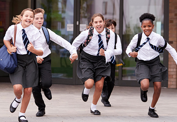 A group of schoolchildren running in a school playground.